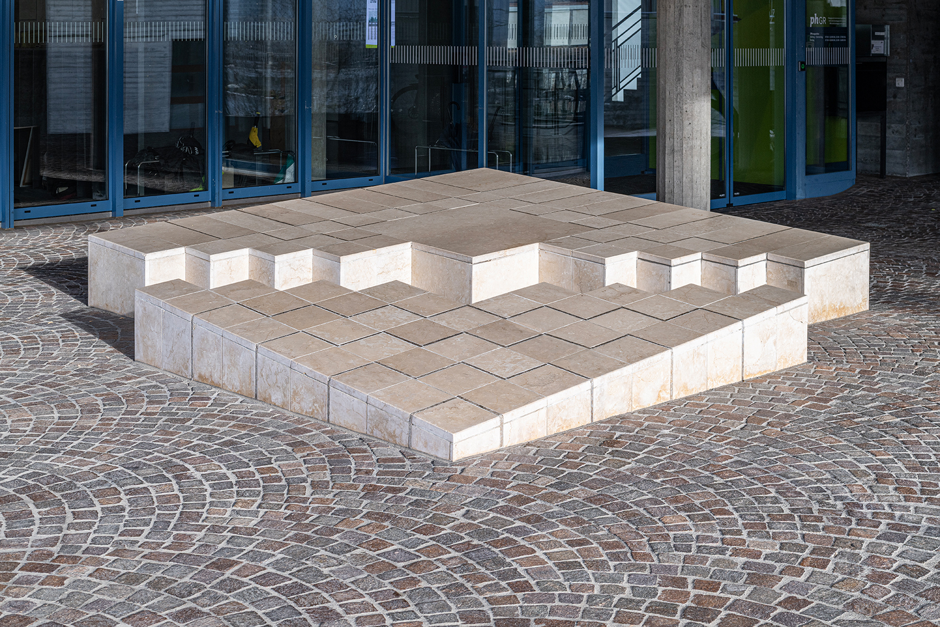 Adriana Grass-Marques, ohne Titel, 1983, aufgebrochener Quader, Inkrustation, Kalkstein, am Gebäude der Pädagogischen Hochschule Graubünden